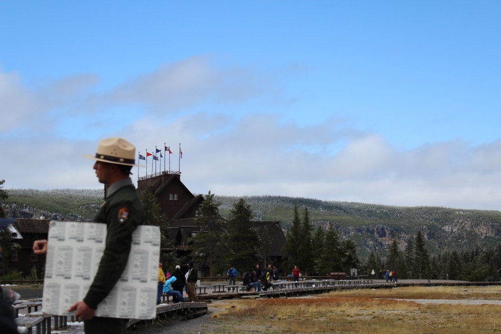 image of a park ranger holding a poster board in front of the old faithful inn