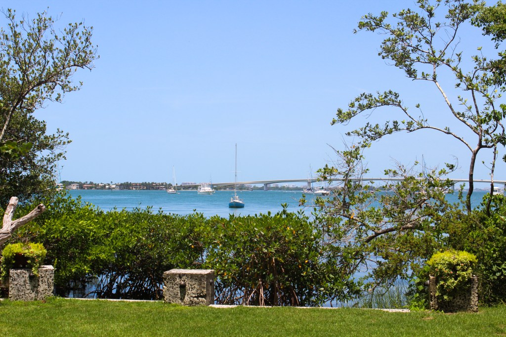 View of the bay from inside Marie Selby Botanical Garden with boats and a bridge in the background