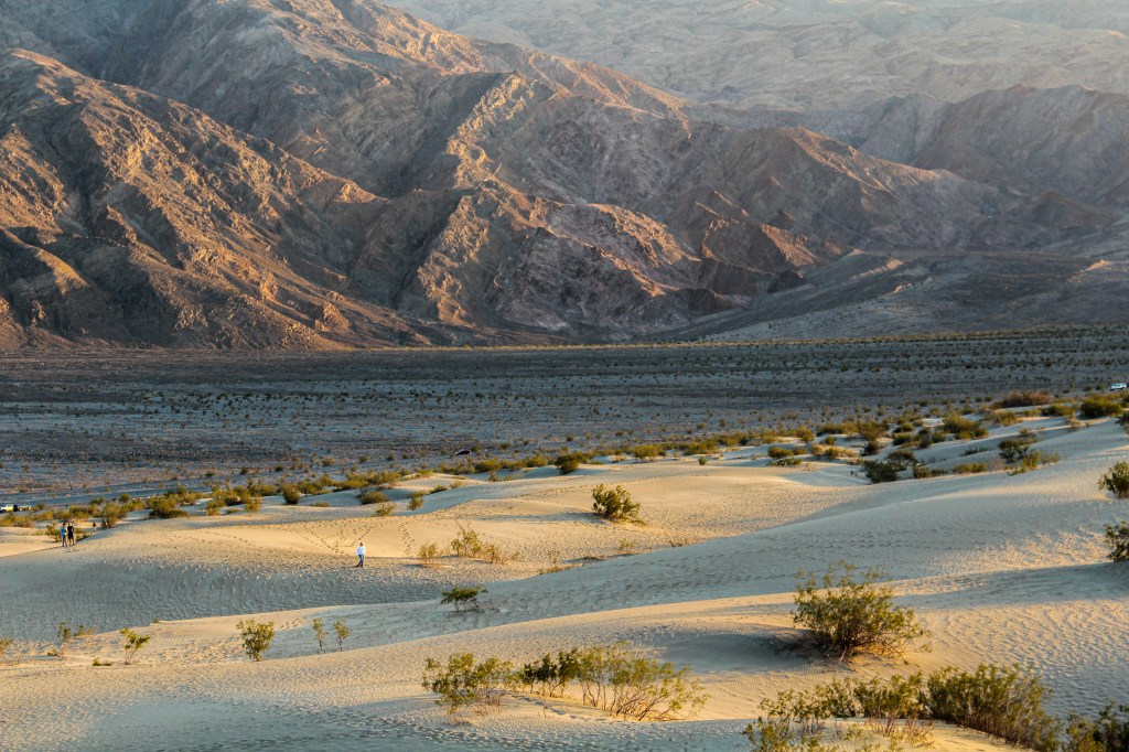 Sunset at the Mesquite Flat Sand Dunes, image of the sand dunes meeting the mountains with a person in middle ground wandering 
